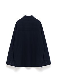 Camicia oversize blu navy in tessuto testurizzato, con colletto e polsini bottonati. Presenta un orlo spaccato e un motivo orizzontale sulla parte posteriore.