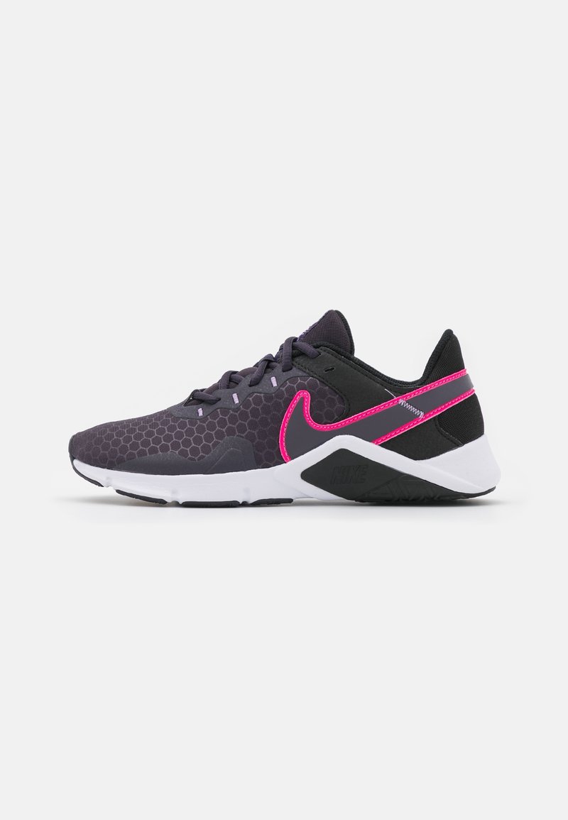 Nike sportschoen met een zwart en paars honingraatpatroon, roze accenten, een witte tussenzool en een geprofileerde zwarte buitenzool.