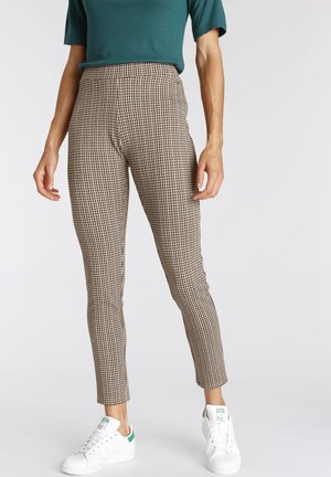 Trousers in a brown and beige houndstooth pattern, tailored fit, high-waisted, with ankle length and paired with white sneakers.