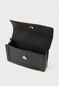 Crni pravokutni kožni clutch s zlatnom kopčom i lancem, preklop otvoren pokazuje tkaninski unutarnji dio i malu džep.