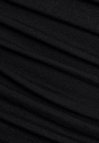 Nærbillede af sort ribstrikket stof med vandrette folder, der viser detaljeret tekstur og syningsmønstre.