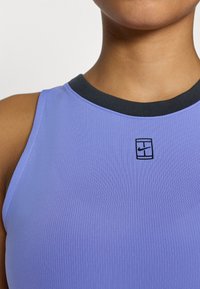 Μωβ ριμπ μπλουζάκι χωρίς μανίκια με μαύρο ριμπ λαιμόκοψη και μικρό μαύρο λογότυπο Nike στο κέντρο του στήθους. Εφαρμοστό σχέδιο με λεία υφή.