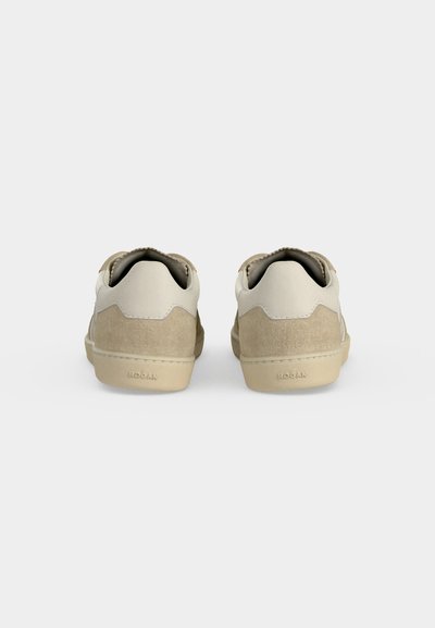 Paire de baskets beige et crème vues de dos sur un fond blanc uni.