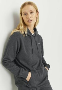 Mørkegrå hettegenser laget av mykt stoff, med en frontlomme, justerbar snor i hetta og lite logo på brystet.