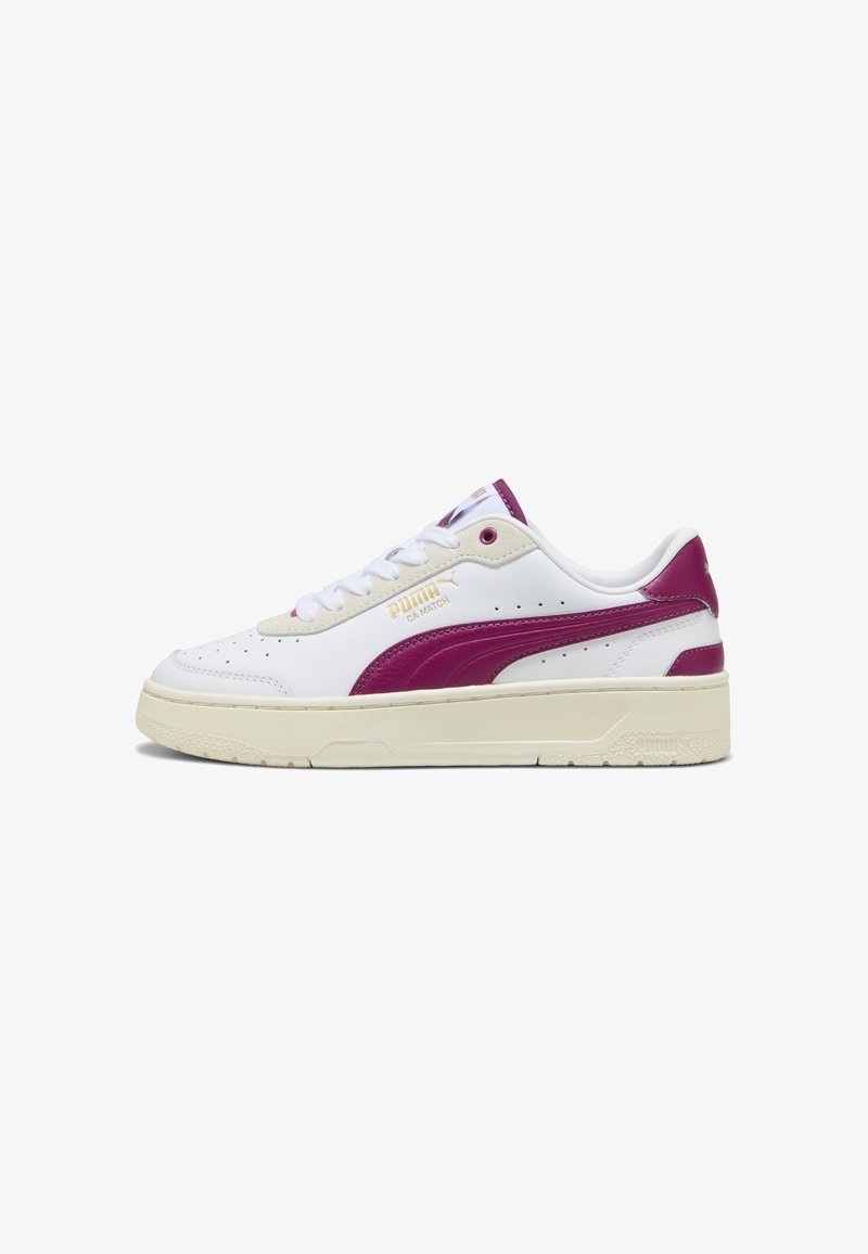 Białe skórzane sneakersy z ciemnoróżowymi akcentami, zaokrąglonym noskiem i teksturowaną gumową podeszwą. Posiadają złote logo Pumy po boku.