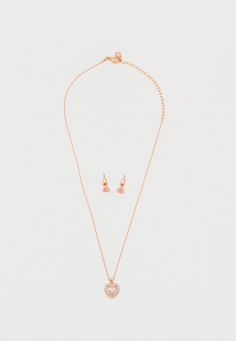 Κολιέ ροζ χρυσού με μενταγιόν σε σχήμα καρδιάς με ροζ πολύτιμο λίθο και ταιριαστά σκουλαρίκια με ροζ πολύτιμους λίθους σε λευκό φόντο.