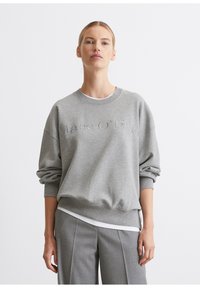 Sivá mikina s okrúhlym výstrihom a vyrazeným textom "Marc O'Polo". Má voľný strih, zrolované rukávy a jemnú tkaninu.