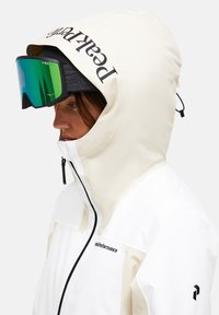 Hvid og creme skijakke med justerbar hætte, lynlåslukning og logo-detalje. Teal spejlgoggles. Glat, vandtæt stofstruktur.