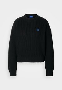 Pull en maille côtelée noire avec col rond, manches longues, ourlet court et petit logo circulaire bleu sur le côté gauche de la poitrine portant l'inscription "HUGO".