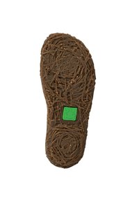 Suela de zapato de goma marrón con un aspecto texturizado similar a la madera y un logo de rana verde en el centro. Patrones circulares por toda la superficie.