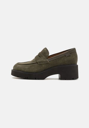 Mocassino verde in suede con tacco largo e blocco e suola in gomma testurizzata. Presenta una parte anteriore cucita e una sottile etichetta sul retro.