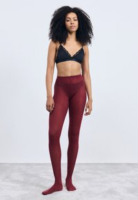 Burgunderfarbene Strumpfhosen mit hoher Taille und glatter Textur, kombiniert mit einem schwarzen Bralette mit Spitze. Minimalistisches Design, volle Abdeckung.