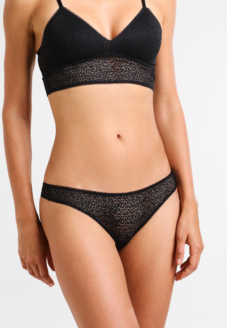 Set di reggiseno e culotte in pizzo nero con un motivo testurizzato, spalline morbide e un bordo in pizzo coordinato. Il reggiseno ha una forma triangolare; le culotte sono a vita bassa.
