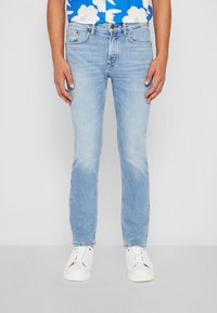 Lichtblauwe denim jeans met een slim fit, lichte vervaging en whiskering, gecombineerd met witte sneakers. Het ontwerp heeft de standaard vijf-pocket stijl.