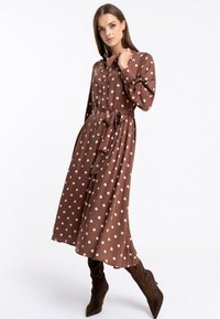 Brązowa midi sukienka w kropki z kołnierzykiem, długimi rękawami i przewiązanym w pasie. Miękka, gładka tkanina; charakteryzuje się zwiewną sylwetką.