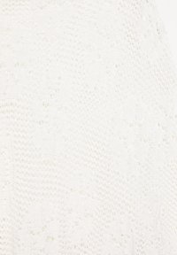 Tissu tricoté blanc avec un motif délicat en dentelle texturée comprenant des motifs floraux et géométriques.