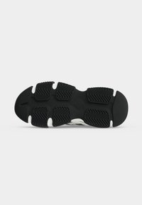 Zwart-witte sneakerzool met gesegmenteerde rubberen loopvlakken met een visgraatpatroon voor grip op een witte achtergrond.