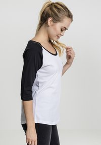 Zwart-witte t-shirt met driekwartmouwen, voorzien van een ronde halslijn, zacht katoenen materiaal en een ontspannen pasvorm. Geen patronen of accenten.