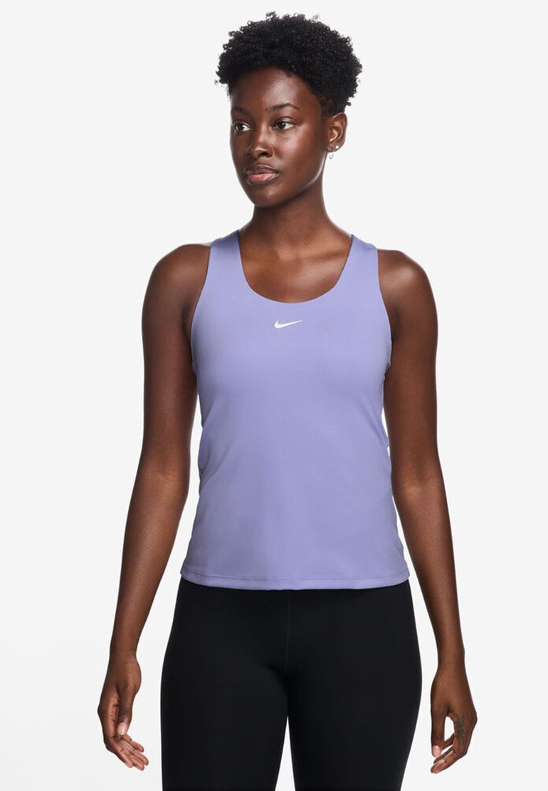 Heledad lilla jooksutop, ümmarguse kaelusega ja valge Nike logo, kombineeritud mustade liibuvate legging'itega. Sile kangatekstuur.