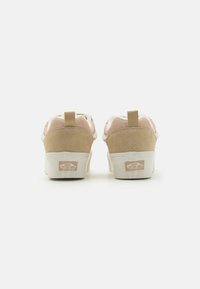 Tan and pink suede sneakers with white accents, featuring a high-top design, textured panels, and a branded white rubber sole.