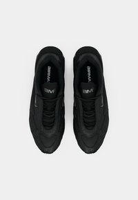 Μαύρα αθλητικά παπούτσια με υφασμάτινη επιφάνεια με υφή, καουτσούκ σόλα και χαρακτηριστικό κυρτό σχέδιο. Διαθέτουν μαύρα κορδόνια και ασημένιο λογότυπο.