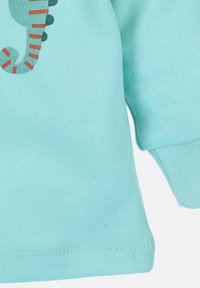 Jasnoniebieska bawełniana koszulka z krótkim rękawem z nadrukiem konika morskiego w zielone i czerwone paski; posiada okrągły dekolt.