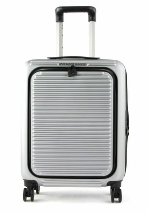 Srebrna, twarda walizka z poziomym żłobionym wzorem, z wysuwaną rączką i czterema czarnymi kółkami. Posiada zamek błyskawiczny oraz logo na górze.