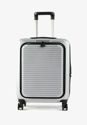 Srebrna, twarda walizka z poziomym żłobionym wzorem, z wysuwaną rączką i czterema czarnymi kółkami. Posiada zamek błyskawiczny oraz logo na górze.