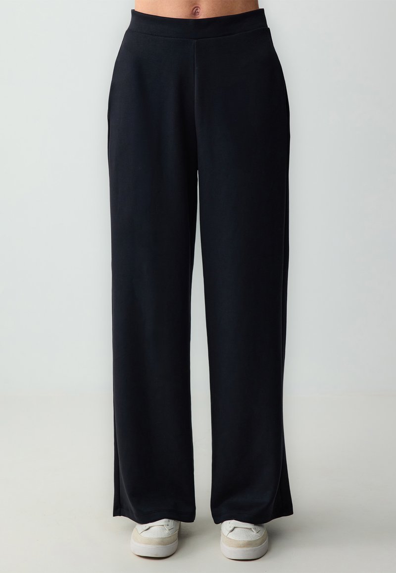 Zwarte wijde broek met een gladde textuur en elastische tailleband, met een rechte pasvorm en een lengte die tot op de grond valt.