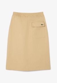 Jupe beige avec une taille élastique, dotée d'une poche latérale et d'un petit logo vert. Fabriquée en tissu lisse et léger.