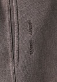 Brauner Baumwollmischstoff mit gerippter Textur. Verfügt über eine dezente Branding in dunklem Faden entlang der Seite. Glattes, lässiges Design.