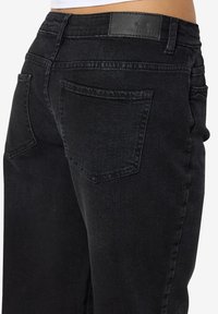 Zwarte denim jeans met een gladde textuur, met een hoge taille, twee achterzakken en een leren label op de tailleband.