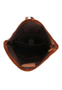 Öppen brun läderväska som visar ett mörkt tyginteriör med en liten ficka och en läderlapp nära botten.