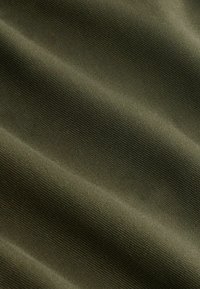 Khaki látka s hladkou texturou, zdobená jemnými žebrováními a vlnami, které vytvářejí měkký vzhled. Vhodná pro různé použití.