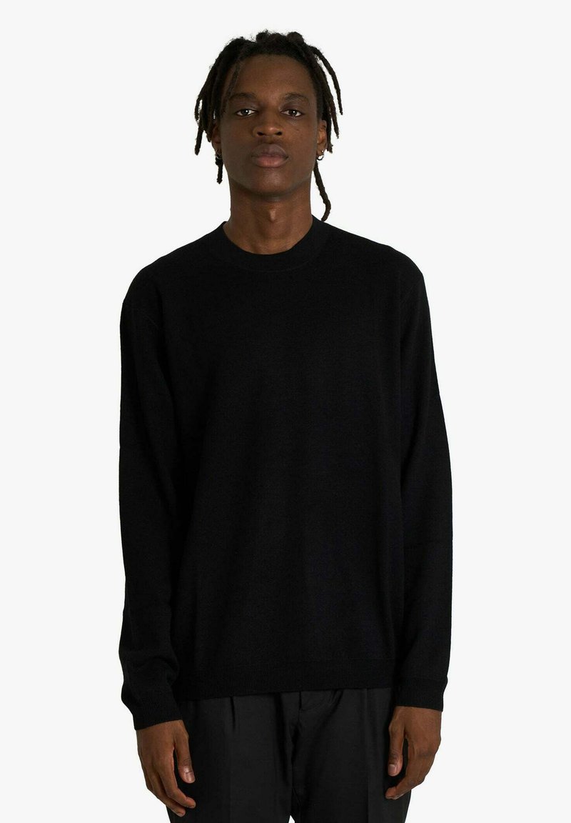 Maglione nero a girocollo realizzato in tessuto morbido con maniche lunghe e vestibilità rilassata. Design minimale, senza motivi o accenti visibili.