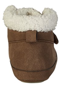Braune Wildleder-Hausschuhe mit weißem, lockigem Fleece-Futter, das über den Knöchel geschlagen ist, von hinten gezeigt.