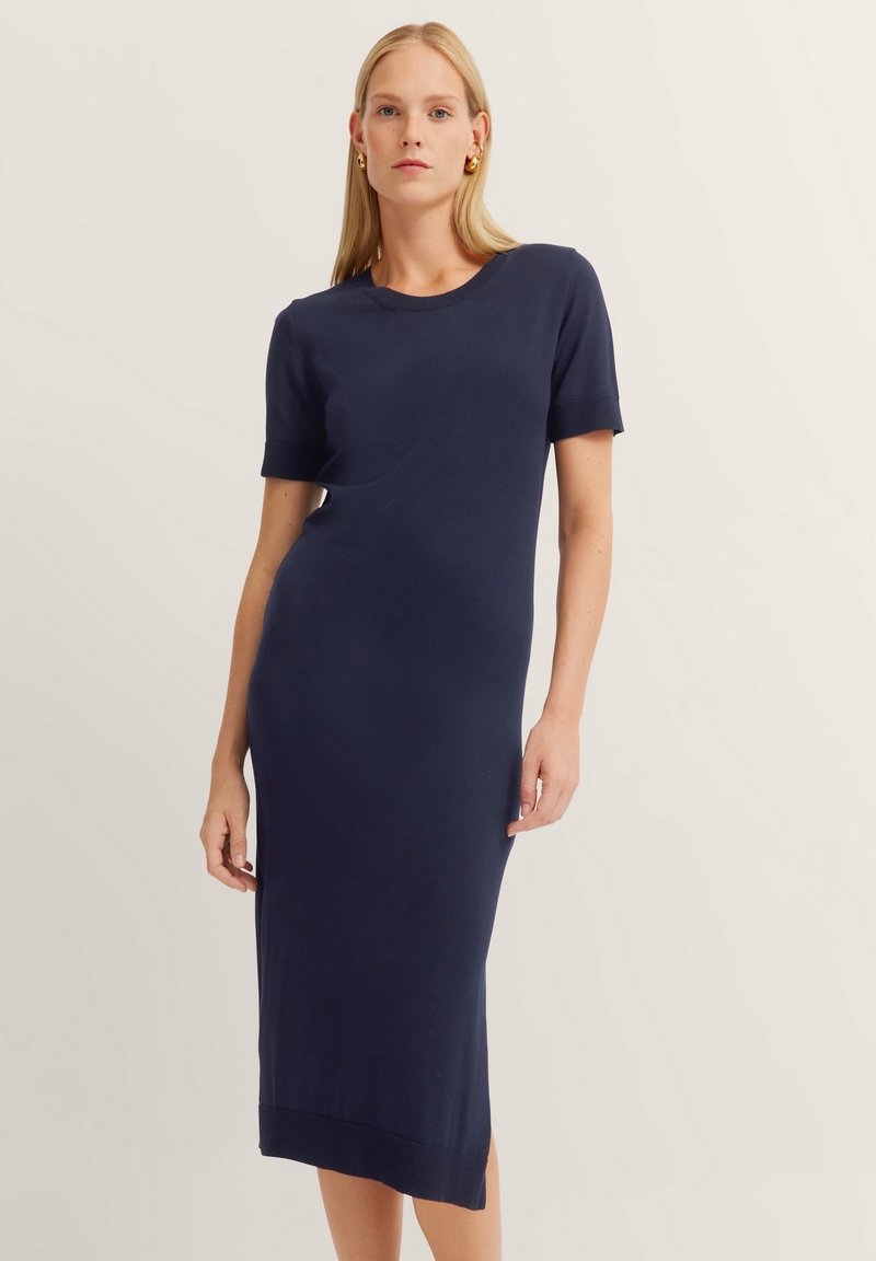 Navyblaues tailliertes Kleid aus Strickstoff. Kurze Ärmel, runder Ausschnitt und knielang mit gerippten Saumdetails. Schlichtes und sauberes Design.