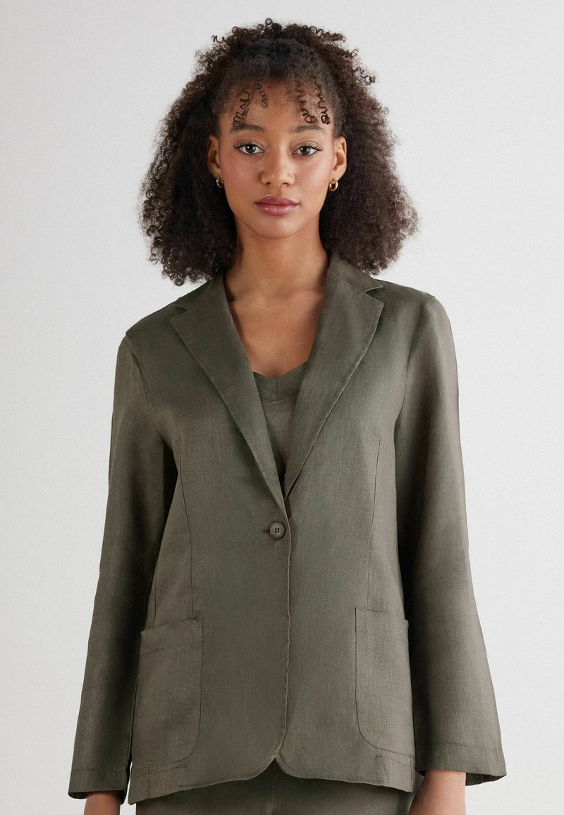 Olivgrön linneblazer med en knapp, slagkrage och två framfickor. Slät struktur och avslappnad passform med trekvartslånga ärmar.