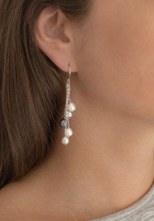 Silver hanging earrings with three pearls: two white, one grey, connected by a delicate chain. Textured surface, minimalistic design.