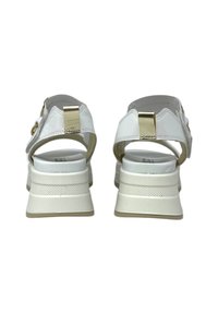 Weiße Plattform-Sandalen mit einer strukturierten Sohle, die einen goldenen Akzent an der Ferse und ein offenes Rückendesign aufweisen. Aus glattem Leder.