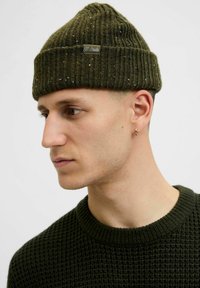 Mørkegrøn strikket hue med ribbet struktur og farvestriber. Har et lille mærke på fronten. Bæres sammen med en matchende tekstureret sweater.