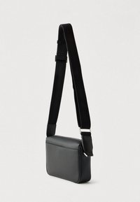 Μαύρο συνθετικό τσαντάκι χιαστί με ορθογώνιο σχήμα, επίπεδη μπροστινή όψη, ρυθμιζόμενο λουρί και λεία υφή.