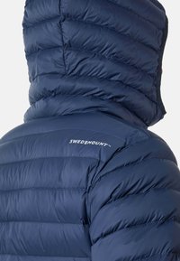 Mörkblå puffjacka med quiltat mönster, med huva och varumärkeslogotypen "SWEDEMOUNT" på övre ryggen. Materialet är glänsande och glatt.