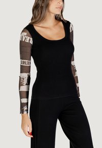 Schwarzes, gestreiftes Langarmtop mit transparenten bedruckten Ärmeln, die Texte und grafische Muster zeigen. Rundhalsausschnitt, figurbetonte Passform, glatte Textur.