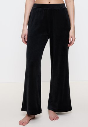 Zwarte fluwelen broek met een wijde pijpdesign, elastische tailleband en zachte textuur. De zoomafwerking is netjes zonder versieringen.