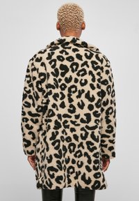 Bež kaput s leopard uzorkom izrađen od teksturirane, plišane tkanine. Ima ovratnik, duge rukave i ležeran kroj, prikazan sa stražnje strane.