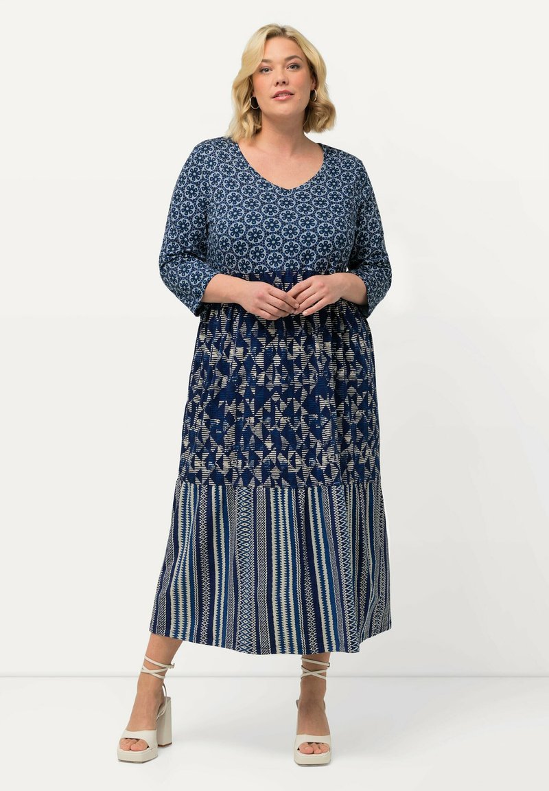 Abito navy con maniche a tre quarti, scollatura a V, corpino a fantasia e gonna a righe; presenta design floreali e geometrici a contrasto.