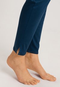 Leggings azul marino con una textura suave, que presentan un diseño recortado y un detalle de abertura en los tobillos. Tela suave con un aspecto ajustado.