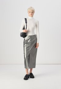 Balta garām piedurknēm turtlenecka tīrā kopā ar sudraba metālisku midi svārku ar priekšējo izgriezumu. Melna plecu soma un masīvas melnas kurpes.
