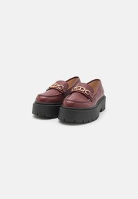Bordeaux leren instappers met een chunky zwarte plateauzool, voorzien van een gouden kettingaccent over de wreef. Gladde textuur, ronde vorm.